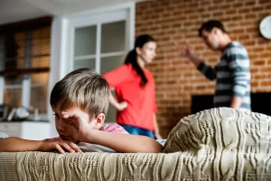 child on the couch as parents fight in the background